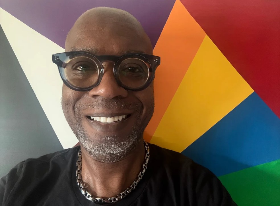 Author standing in front of a rainbow prism painting.